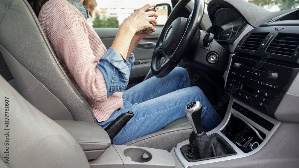 Woman drinking coffee while driving a car