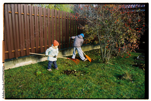 Children raking leaves in the backyard on a sunny autumn day photo