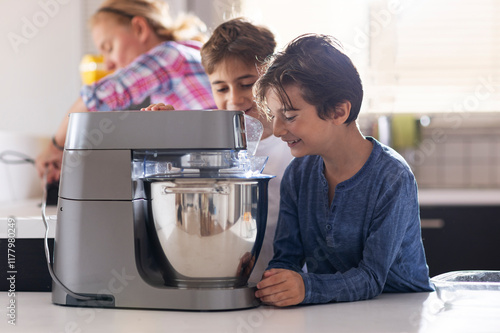 Two children enjoying baking with a kitchen mixer in a sunny kitchen photo