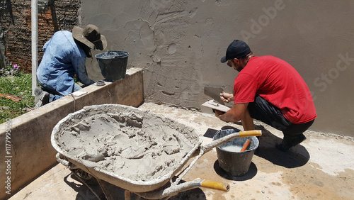 Profissionais no trabalho de construção do muro de cimento.