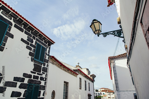 Charming narrow street with stone and white buildings in daylight photo