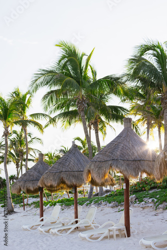 Tropical beach paradise with palm trees and straw umbrellas photo