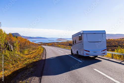 Motorhome driving on a scenic road in Kiruna, Sweden, with autumn foliage and beautiful lake views. photo