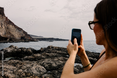 Lady using a mobile to take pictures of the seascape of Tacoron Beach photo