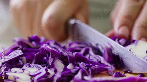 Female hands cutting and slicing purple cabbage with knife on wooden board
