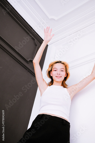 Young woman posing with arms raised in a modern interior  photo