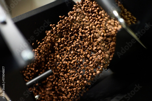 Freshly roasted coffee beans cascading from the roaster in a cafe photo