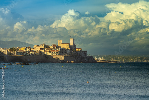 Vielle ville d'Antibes lors d'un couché de soleil avec un ciel nuageux cachant les alpes en arrière plan photo