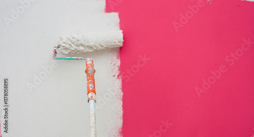 A paint roller is painting with white and orange pink teindoors