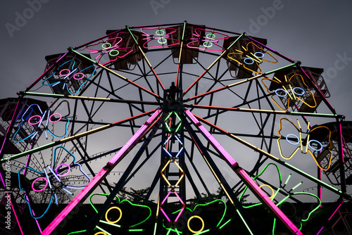 A ferris wheel decorated in neon lights with butterflies at a carnival photo