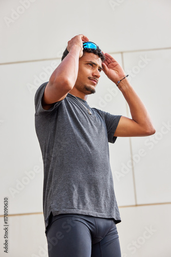 Man adjusting his sunglasses in a modern outdoor setting.
 photo