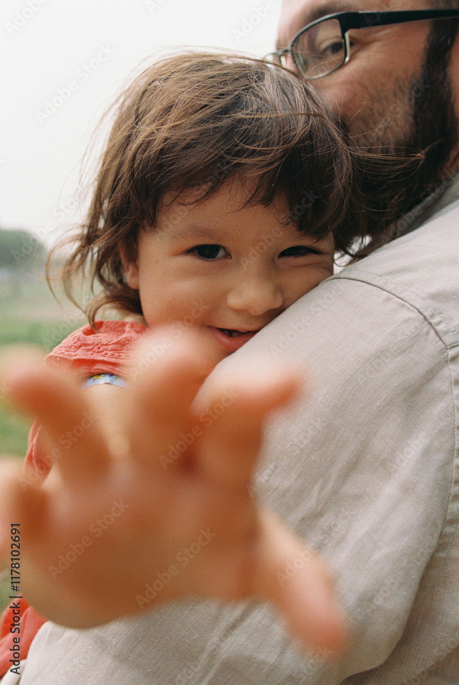 Toddler reaching out while hugging father Toddler reaching out while hugging father