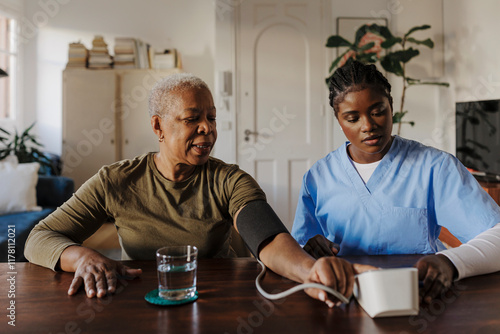 Nurse measuring blood pressure of senior woman at home photo