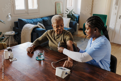 Nurse measuring blood pressure of senior woman at home