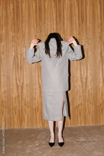 Person Wearing Overcoat Standing Against Wooden Background photo