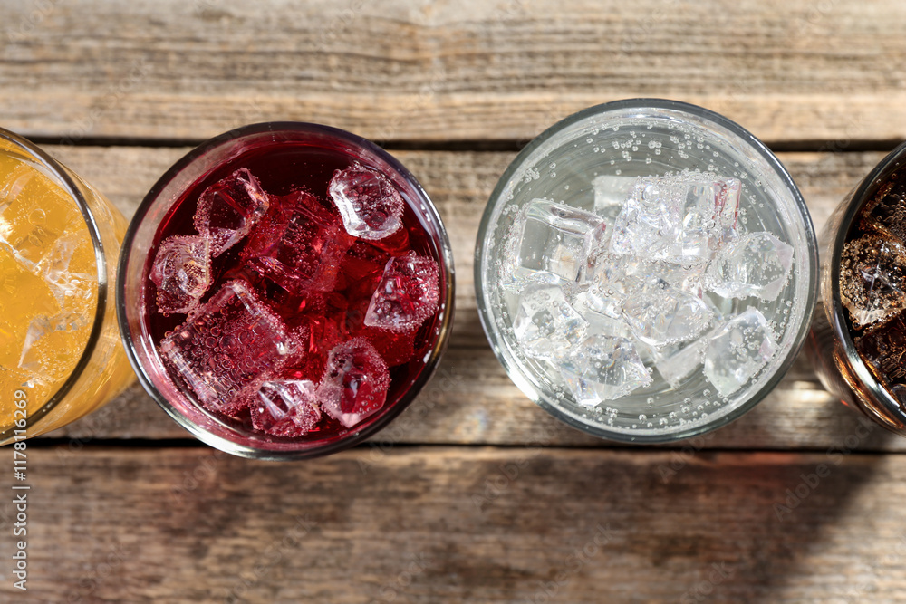 Φωτογραφία Soda water of different flavors with ice cubes in glasses on wooden table, flat