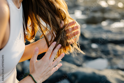 Unknown lay smearing hair care product on the ends of her hairstyle