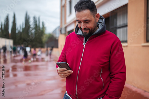 bearded man using a mobile phone next to a soccer field photo