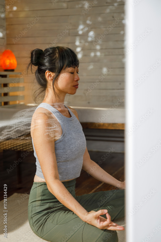 Active woman meditating at home seen through window glass Active woman meditating at home seen through window glass