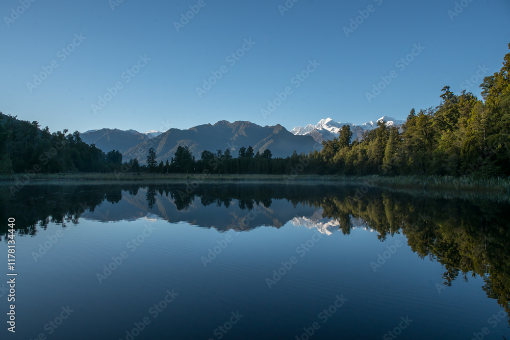 Fototapeta premium Hiking through lush native bush pedestrian footpath around the lakeside of Lake Matheson