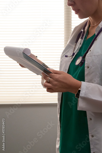 Female doctor reading medical records in hospital room photo