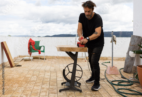 Man using power tool to treat wood photo