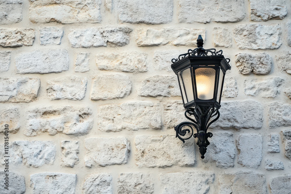 Black iron wall light with adornments on a white brick wall outside an old building in Lle
