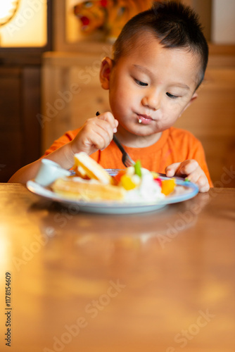 Child Enjoying Delicious Waffles and Fruits on a Plate. photo