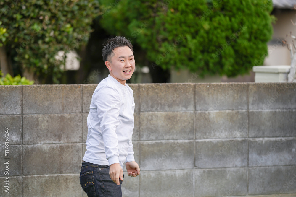 A Japanese parent and child, a man in his 20s and a 6-year-old girl, are enjoying an afternoon playing Frisbee in the walled garden of their home. A Japanese parent and child, a man in his 20s and a 6-year-old girl, are enjoying an afternoon playing Frisbee in the walled garden of their home.