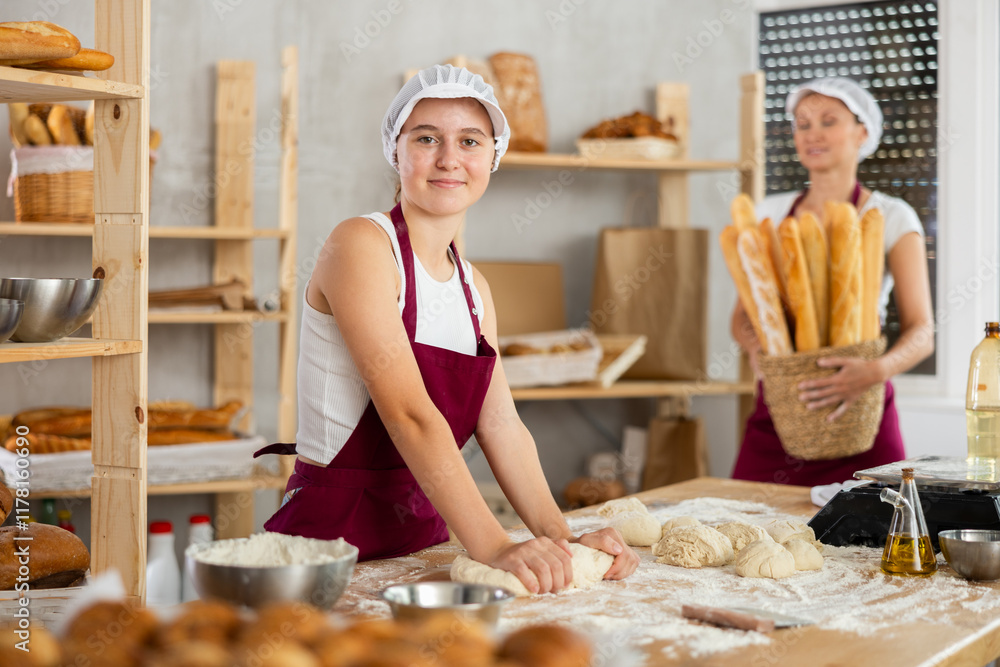 Smiling bakers at work and baking baguettes, buns and delicious bread. Women bakers prepare raw dough, knead it and make French baguettes. Smiling bakers at work and baking baguettes, buns and delicious bread. Women bakers prepare raw dough, knead it and make French baguettes.
