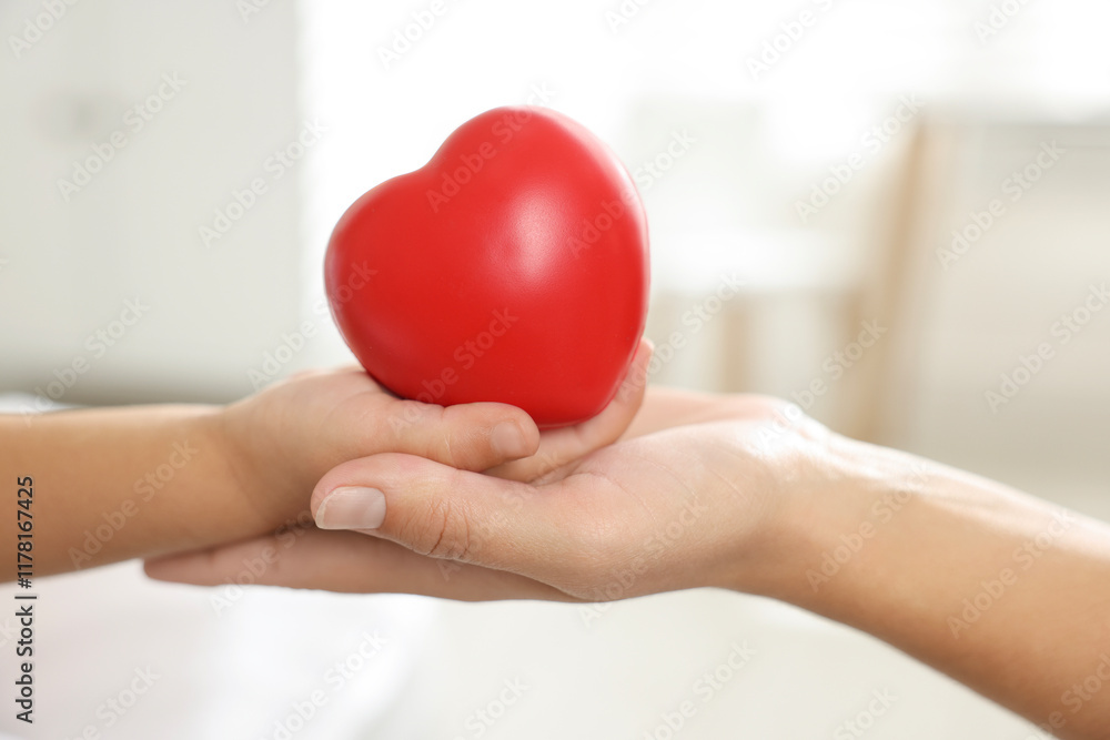 Little girl and her mother with red heart figure indoors, closeup Little girl and her mother with red heart figure indoors, closeup