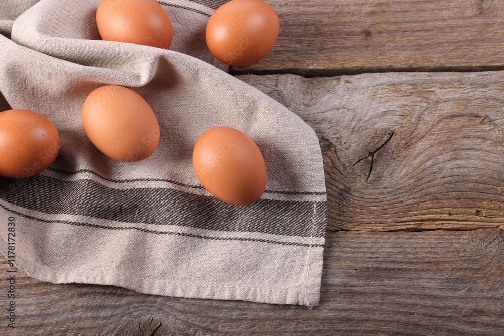 Many fresh eggs and towel on wooden table, flat lay. Space for text Many fresh eggs and towel on wooden table, flat lay. Space for text