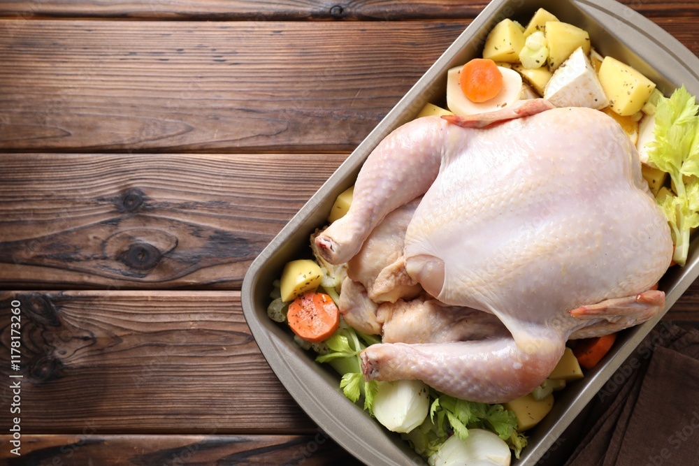 Raw turkey and vegetables in baking dish on wooden table, top view. Space for text Raw turkey and vegetables in baking dish on wooden table, top view. Space for text