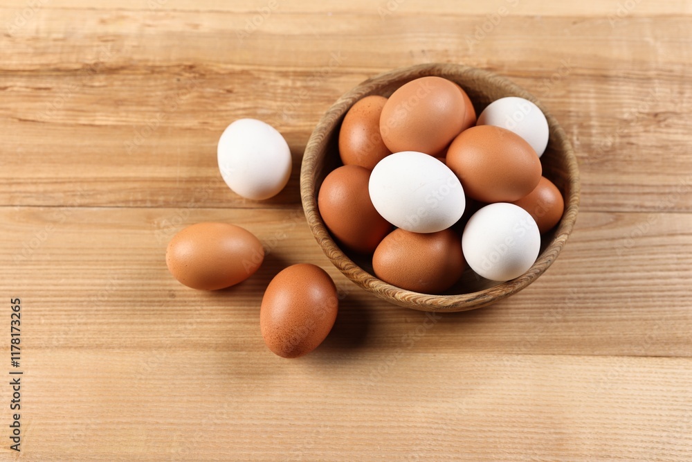 Raw eggs in bowl on wooden table, closeup Raw eggs in bowl on wooden table, closeup