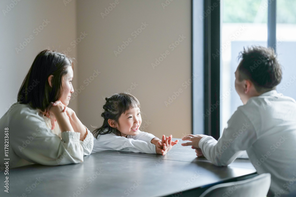 A Japanese parent and child, a woman in her 30s, a man in his 20s, and a 6-year-old girl, are playing with their hands at a table in their living room. A Japanese parent and child, a woman in her 30s, a man in his 20s, and a 6-year-old girl, are playing with their hands at a table in their living room.