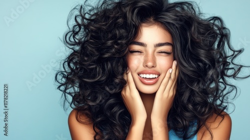 Smiling young hispanic female with curly hair against blue background