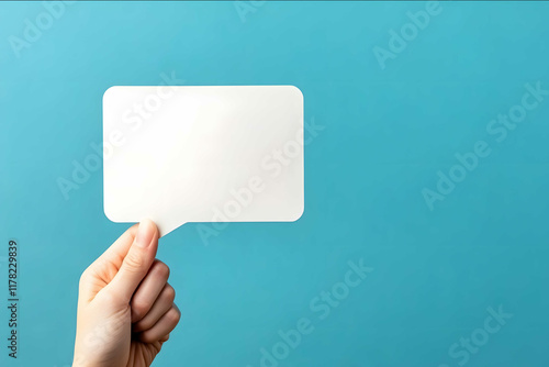 Photo of A hand holding an empty speech bubble on blue background minimalistic stock photo in light and bright style with copy space area photo