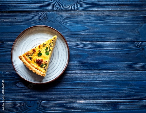 slice of homemade quiche lorraine on a dark blue wooden table top view copyspace photo