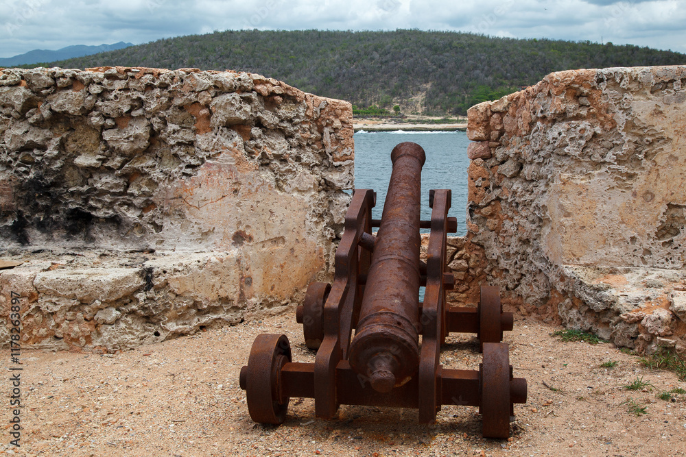 Historical bronze cannon at the fortified walls of Castillo del Morro or San Pedro de la Roca fortress XVII century fortress, and the entrance of Santiago de Cuba bay.
