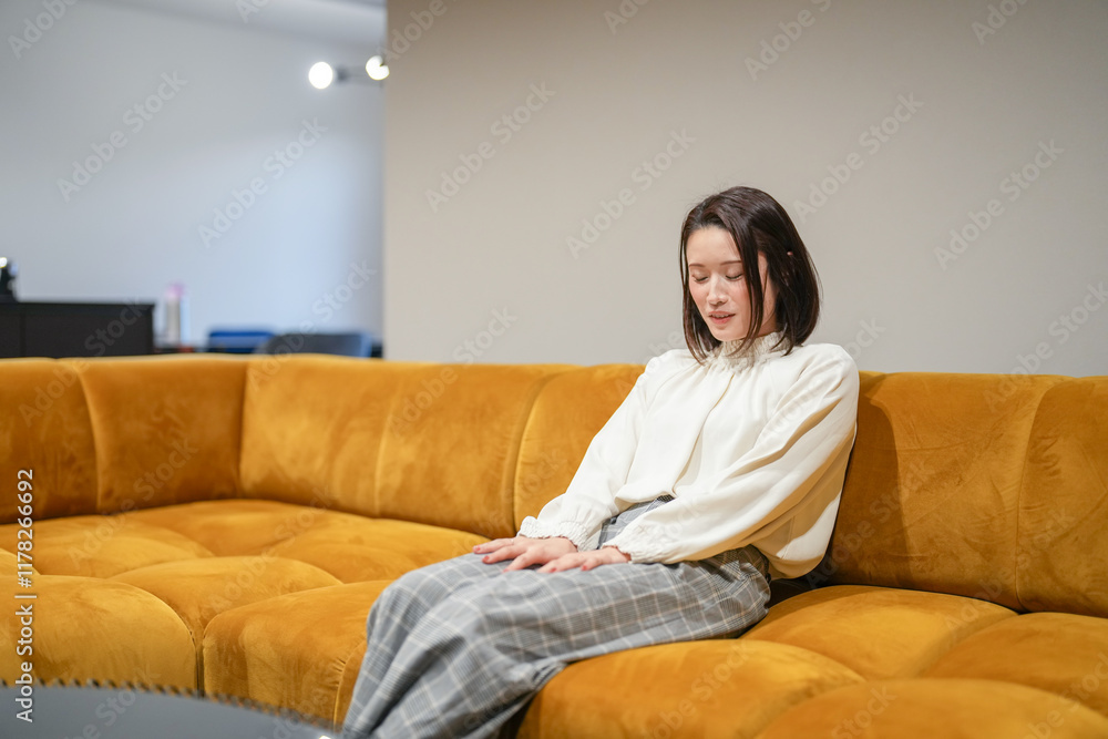A Japanese woman in her 30s is relaxing on the sofa in her living room. A Japanese woman in her 30s is relaxing on the sofa in her living room.