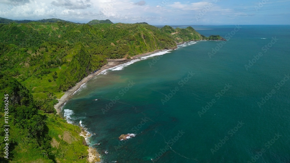 Aerial drone view of coastline with hills and trees, as well as view of coral cliffs and sea with waves from the ocean in Menganti Beach Kebumen Central Java Indonesia Aerial drone view of coastline with hills and trees, as well as view of coral cliffs and sea with waves from the ocean in Menganti Beach Kebumen Central Java Indonesia