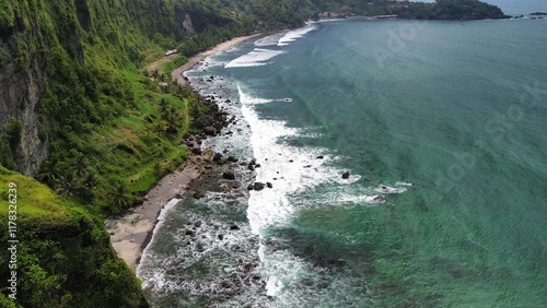 Aerial drone view of coastline with hills and trees, as well as view of coral cliffs and sea with waves from the ocean in Menganti Beach Kebumen Central Java Indonesia photo