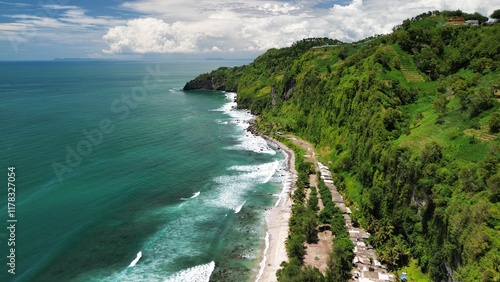 Aerial drone view of coastline with hills and trees, as well as view of coral cliffs and sea with waves from the ocean in Menganti Beach Kebumen Central Java Indonesia