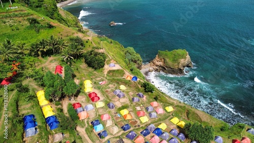 Aerial drone view of coastline with hills and trees, as well as view of coral cliffs and sea with waves from the ocean in Menganti Beach Kebumen Central Java Indonesia