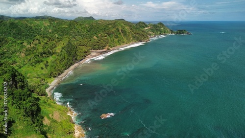 Aerial drone view of coastline with hills and trees, as well as view of coral cliffs and sea with waves from the ocean in Menganti Beach Kebumen Central Java Indonesia