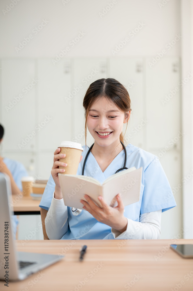 An Asian female medical student in scrubs is sipping a hot drink while reading in a library. An Asian female medical student in scrubs is sipping a hot drink while reading in a library.