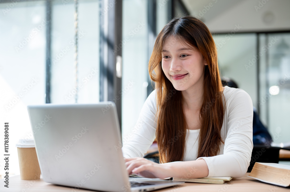 A beautiful, positive Asian female college student working on her laptop at a coffee shop. A beautiful, positive Asian female college student working on her laptop at a coffee shop.