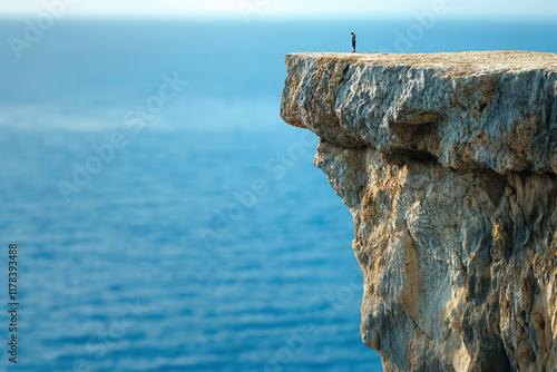 Solitary man on cliff's edge overlooking vast ocean photo