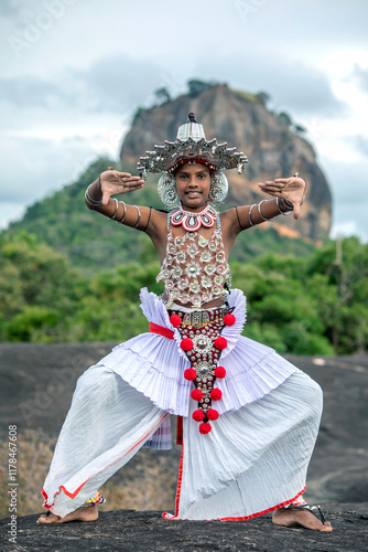 SIGIRIYA, SRI LANKA - JULY 16, 2024 : A Ves Dancer, also known as a Kandyan Dancer or Up Country Dancer performs at Sigiriya in Sri Lanka. In the background stands Sigiriya Rock.