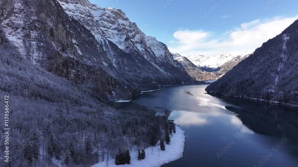 Snow covered Klöntalersee surrounded by alpine peaks and frosted forests in Glarus, Switzerland Snow covered Klöntalersee surrounded by alpine peaks and frosted forests in Glarus, Switzerland